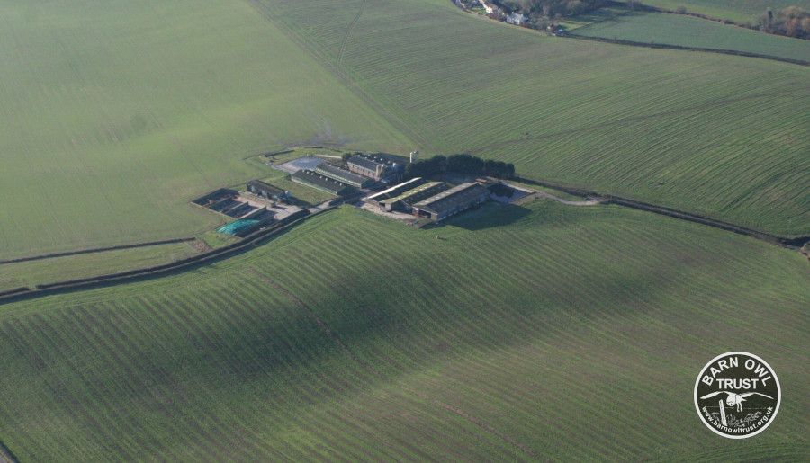 Aerial shot of a complex of modern farm buildings amidst rolling fields